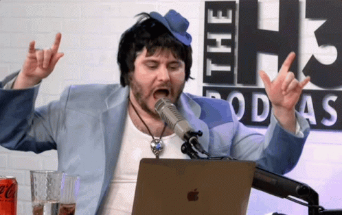 A Man Wearing A Blue Hat Is Singing Into A Microphone In Front Of A Coca Cola Can GIF