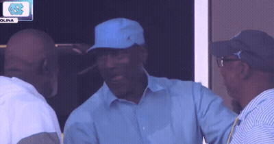 A Man Wearing A Blue Hat Is Talking To Another Man In Front Of A Sign That Says Olina GIF