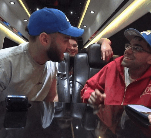 A Man Wearing A Blue Hat With The Letter P On It Talks To Another Man GIF