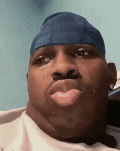 A Man Wearing A Blue Headband Is Crying With A Tear Coming Out Of His Nose . GIF