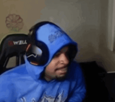 A Man Wearing A Blue Hoodie And Headphones Is Sitting In A Chair In Front Of A Computer . GIF