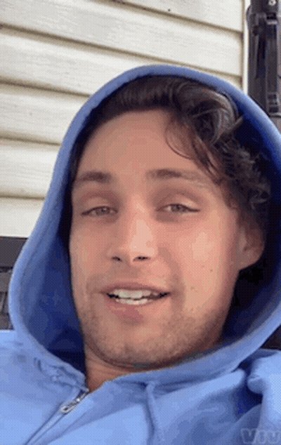 A Man Wearing A Blue Hoodie Is Smiling For The Camera GIF