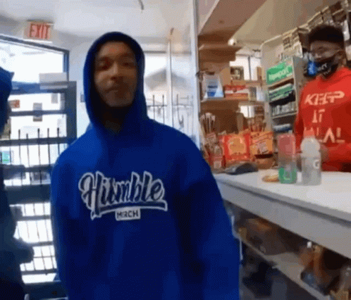 A Man Wearing A Blue Humble Mech Hoodie Stands In Front Of A Counter GIF