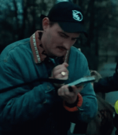 A Man Wearing A Blue Jacket And A Black Hat Has A Camera Strap That Says Minnesota On It GIF