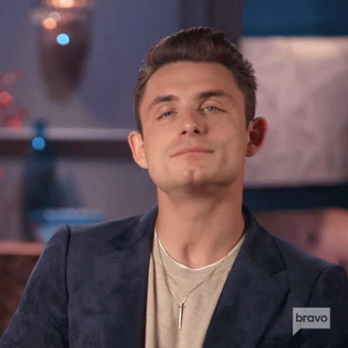A Man Wearing A Blue Jacket And A Necklace With A Bravo Logo GIF
