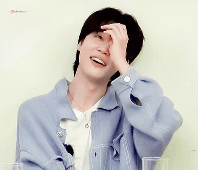 A Man Wearing A Blue Jacket And A White Shirt Is Smiling And Covering His Face With His Hand GIF
