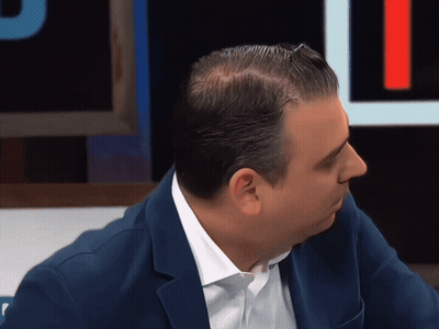 A Man Wearing A Blue Jacket And White Shirt Looks To The Side GIF