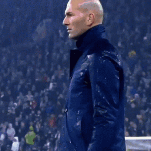 A Man Wearing A Blue Jacket Is Standing In Front Of A Crowd GIF