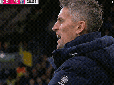 A Man Wearing A Blue Jacket With A Sun On The Sleeve Watches A Soccer Game GIF