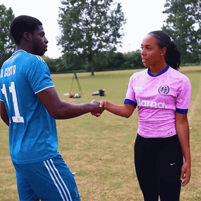 A Man Wearing A Blue Jersey With The Number 11 Shakes Hands With A Woman Wearing A Pink Shirt GIF