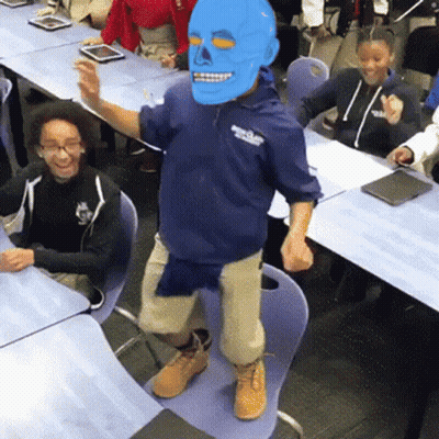 A Man Wearing A Blue Mask Is Dancing In Front Of A Group Of Children GIF