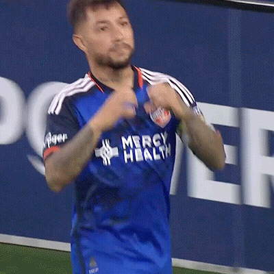 A Man Wearing A Blue Mercy Health Jersey Is Running On The Field GIF
