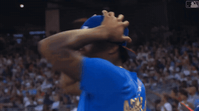 A Man Wearing A Blue Mlb Hat Holds His Hands To His Head GIF