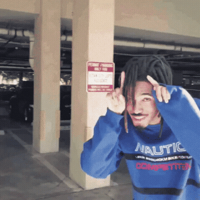 A Man Wearing A Blue Nautica Sweater Stands In Front Of A Permit Parking Sign GIF