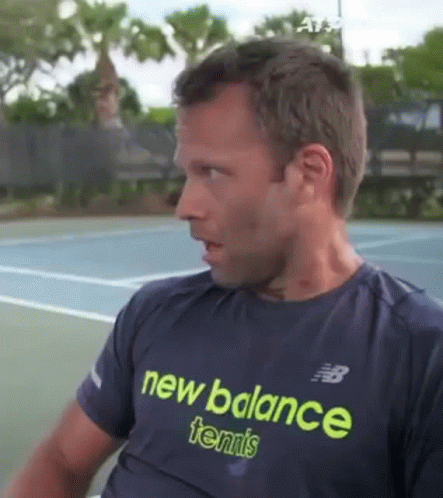 A Man Wearing A Blue New Balance Tennis Shirt Is Sitting On A Tennis Court . GIF