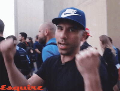 A Man Wearing A Blue Nike Hat Is Standing In A Crowd Of People GIF
