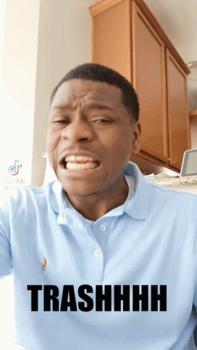 A Man Wearing A Blue Polo Shirt Is Making A Funny Face And Has The Word Trashhhh On His Shirt GIF