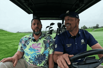 A Man Wearing A Blue Reebok Shirt Is Driving A Golf Cart GIF