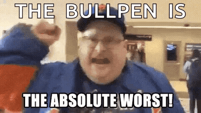 A Man Wearing A Blue Shirt And A Baseball Cap Is Holding His Fist In The Air . GIF