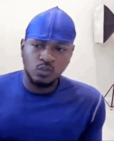 A Man Wearing A Blue Shirt And A Blue Hat Is Making A Funny Face . GIF