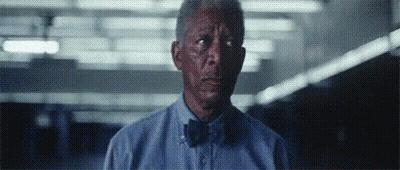 A Man Wearing A Blue Shirt And Bow Tie Is Looking At The Camera . GIF