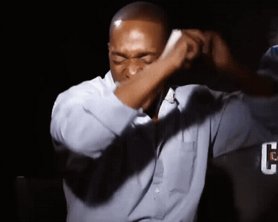 A Man Wearing A Blue Shirt Is Covering His Face With His Hand GIF