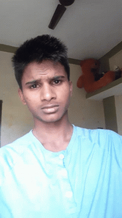 A Man Wearing A Blue Shirt Is Looking At The Camera GIF