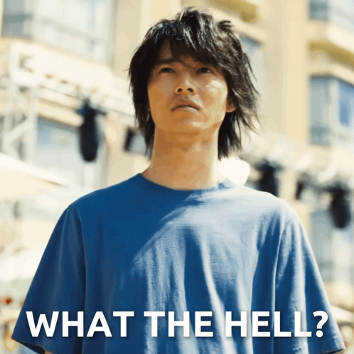 A Man Wearing A Blue Shirt Is Standing In Front Of A Sign That Says What The Hell GIF