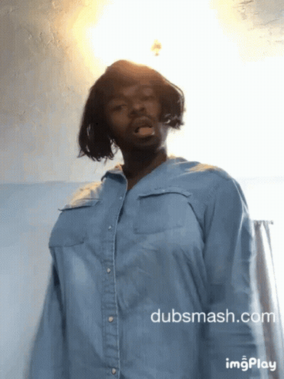 A Man Wearing A Blue Shirt Is Standing In Front Of A Wall With Dubsmash.com Written On The Bottom GIF