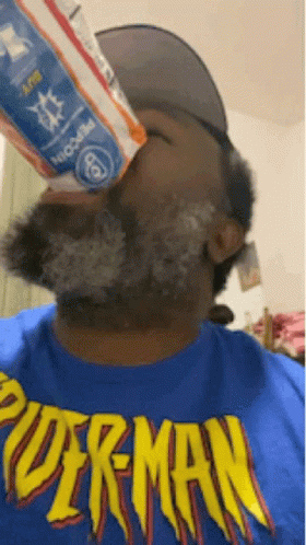 A Man Wearing A Blue Shirt That Says Superman Is Drinking From A Bottle GIF