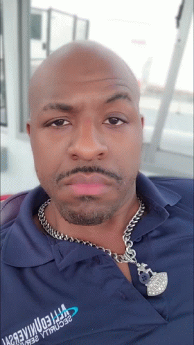 A Man Wearing A Blue Shirt With A Chain Around His Neck Has A Necklace Around His Neck That Says ' Freedom ' GIF