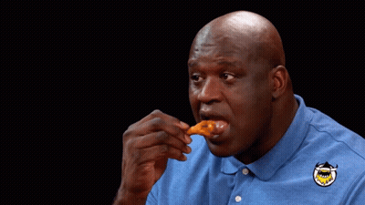 A Man Wearing A Blue Shirt With A Shark On It Is Eating A Piece Of Food GIF