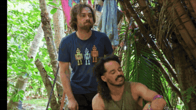 A Man Wearing A Blue Shirt With Robots On It Is Standing Next To Another Man GIF