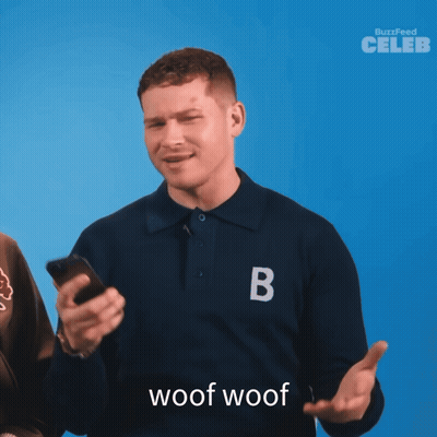 A Man Wearing A Blue Shirt With The Letter B On It Holds A Cell Phone GIF