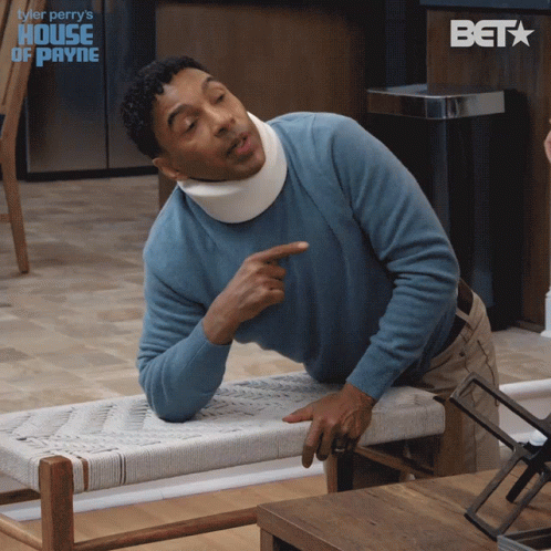 A Man Wearing A Blue Sweater And A Neck Brace Is Pointing GIF
