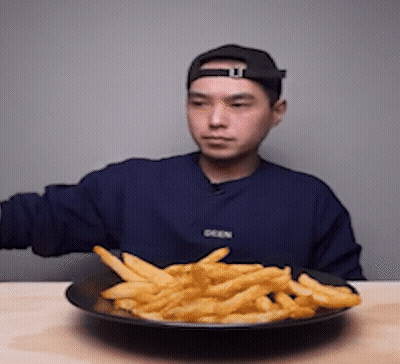 A Man Wearing A Blue Sweater That Says Seen Is Eating French Fries GIF