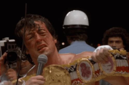 A Man Wearing A Boxing Belt Is Holding A Microphone And Crying GIF