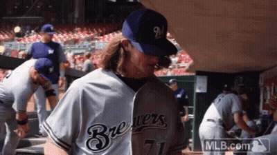 A Man Wearing A Brewers Jersey And A Mlb.com Logo GIF