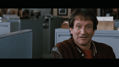 A Man Wearing A Brown Jacket Is Sitting In An Office Cubicle GIF