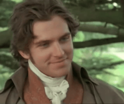 A Man Wearing A Brown Shirt And A White Tie Smiles GIF
