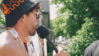 A Man Wearing A Bucket Hat And A Lanyard That Says Sky On It GIF