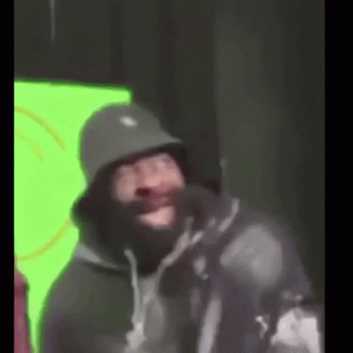 A Man Wearing A Bucket Hat And A Mask Is Making A Funny Face . GIF