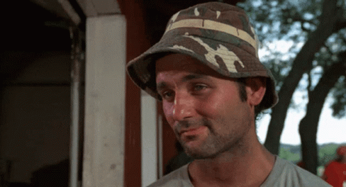 A Man Wearing A Bucket Hat With A Striped Band GIF