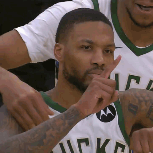 A Man Wearing A Bucks Jersey Is Making A Shhh Gesture GIF