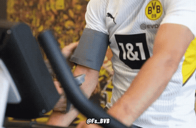 A Man Wearing A Bvb Shirt Rides An Exercise Bike GIF