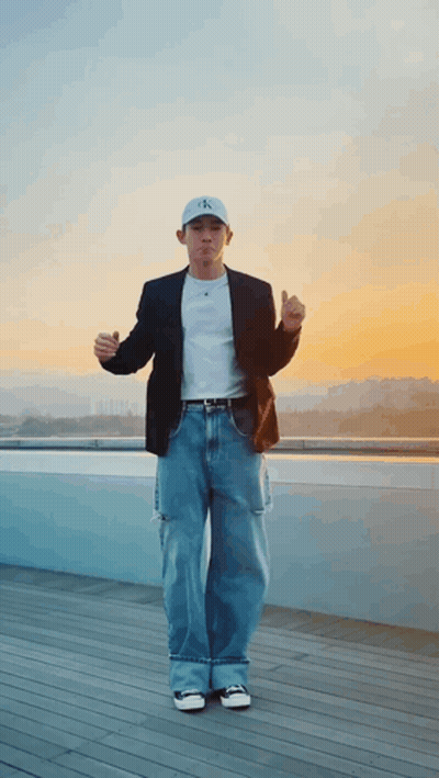 A Man Wearing A Calvin Klein Hat Is Standing On A Balcony GIF