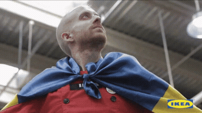 A Man Wearing A Cape With The Ikea Logo In The Corner GIF