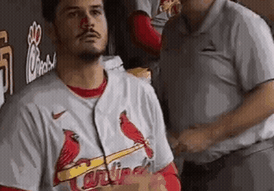 A Man Wearing A Cardinals Jersey Is Standing In A Dugout With A Red Nose . GIF