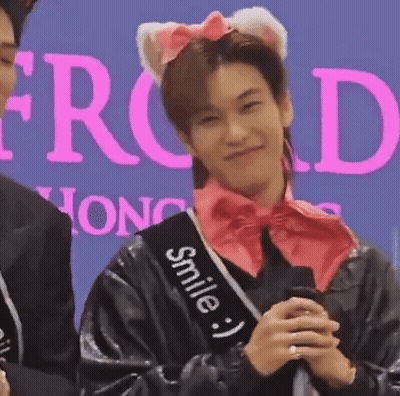 A Man Wearing A Cat Ear Headband And A Sash That Says Smile Is Holding A Microphone And Smiling . GIF