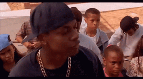 A Man Wearing A Chain Around His Neck Is Standing In A Crowd Of People GIF